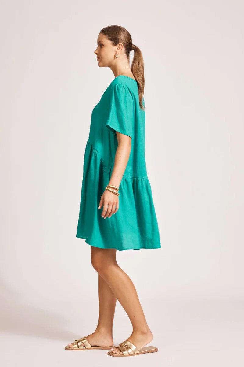 Woman wearing a teal dress on a plain background