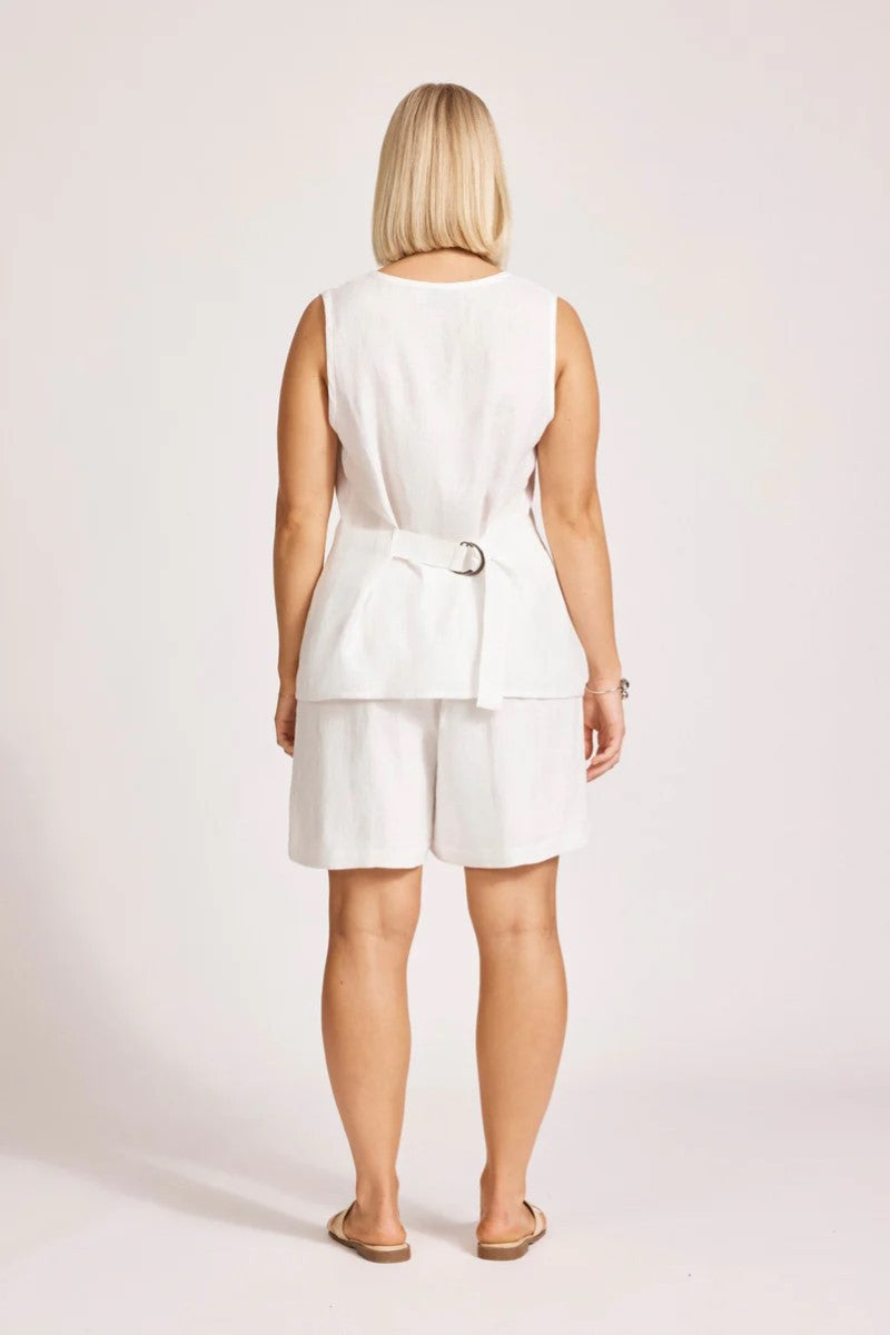 Woman wearing a white sleeveless top and shorts set on a plain background