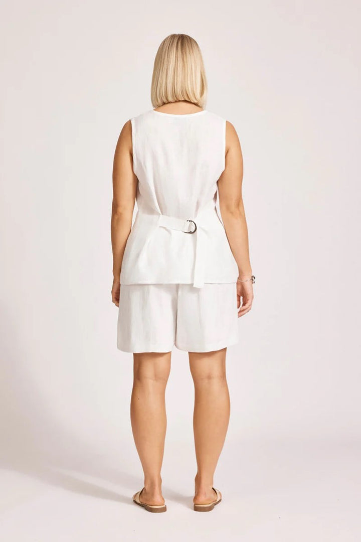 Woman wearing a white sleeveless top and shorts set on a plain background