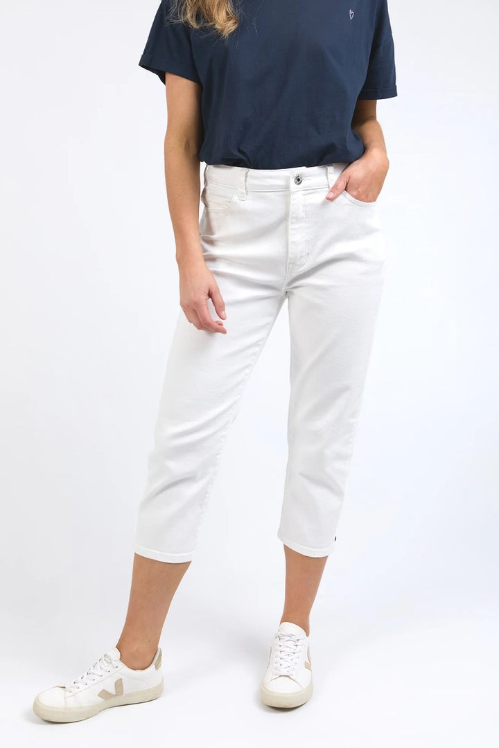 Person wearing a navy t-shirt and white jeans on a white background
