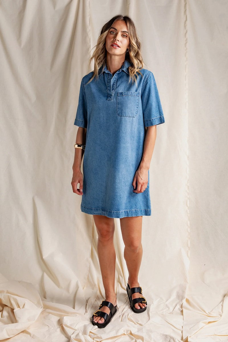 Woman wearing a blue denim dress against a plain background