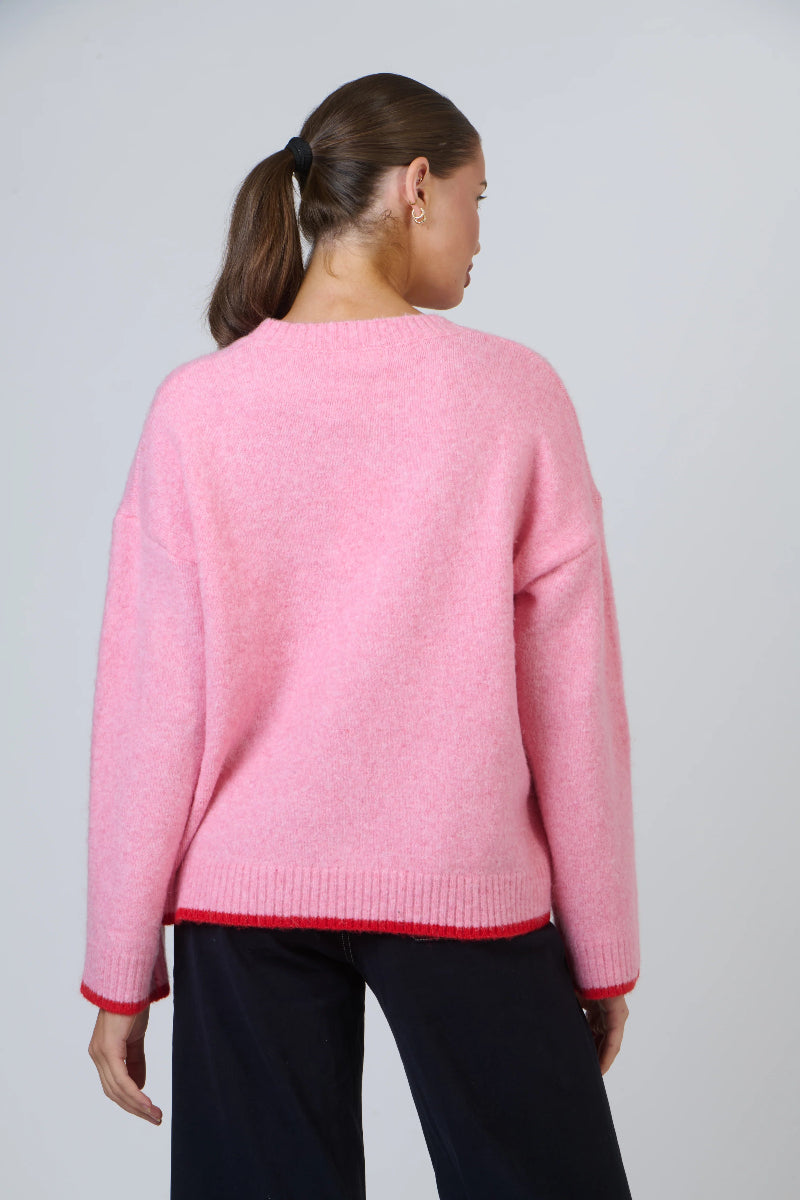 Person wearing a pink sweater with a plain background