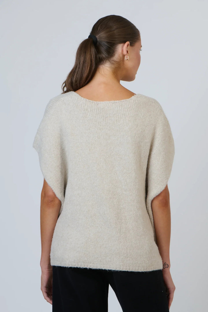 Woman wearing a beige sweater against a plain background