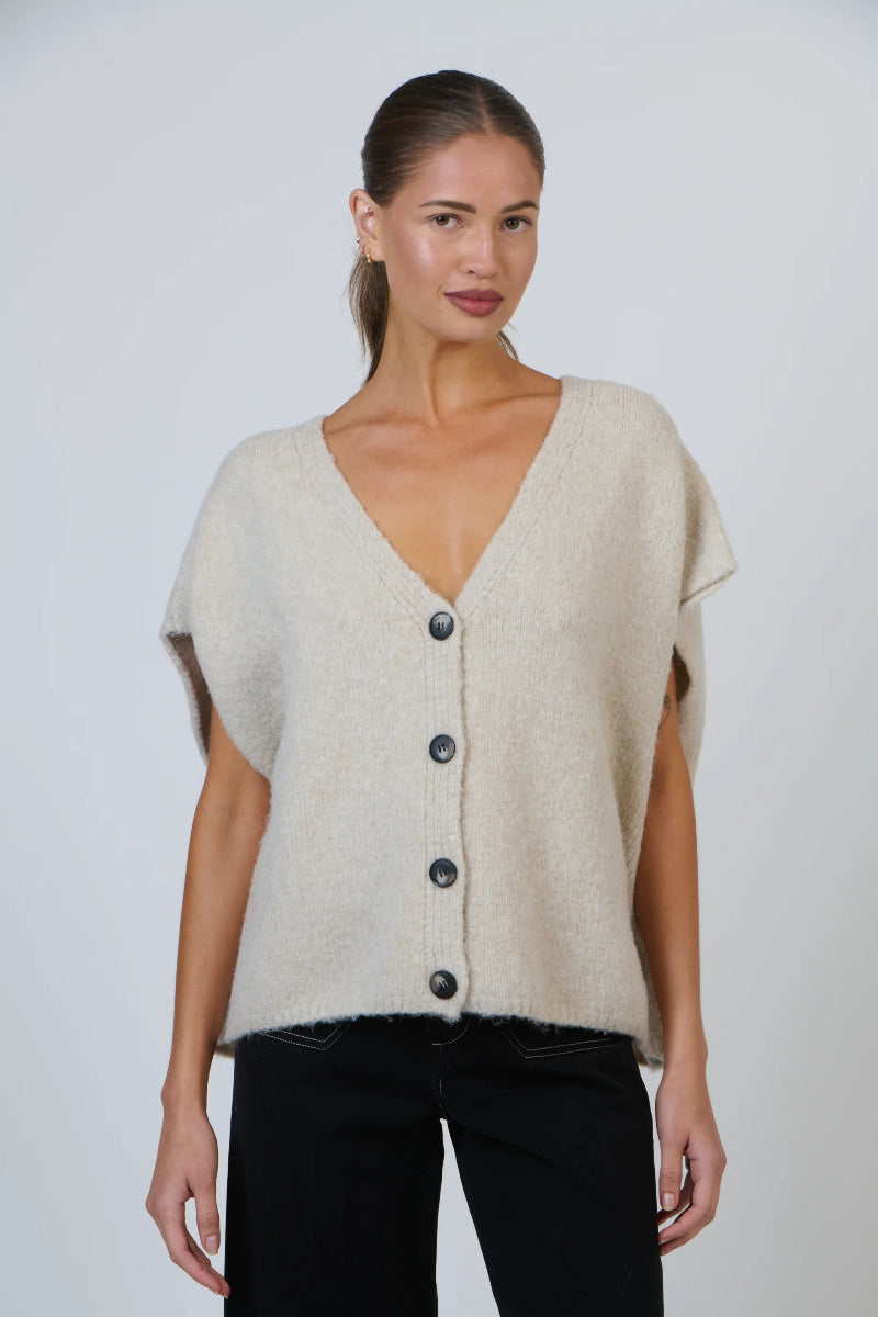 Woman wearing a beige cardigan on a plain background