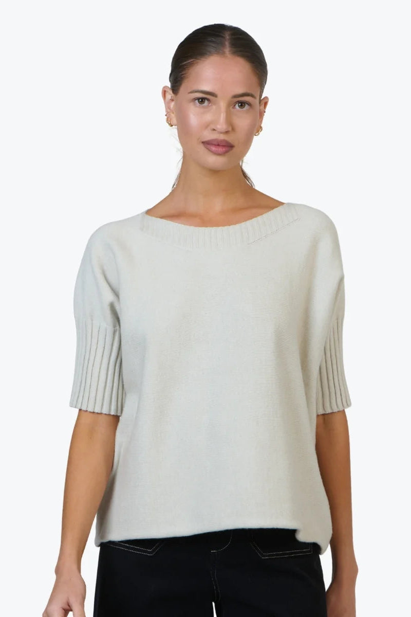 Woman wearing a beige sweater with a plain background