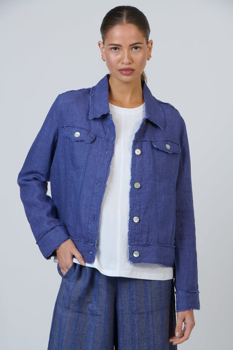Woman wearing a blue denim jacket over a white shirt on a plain background
