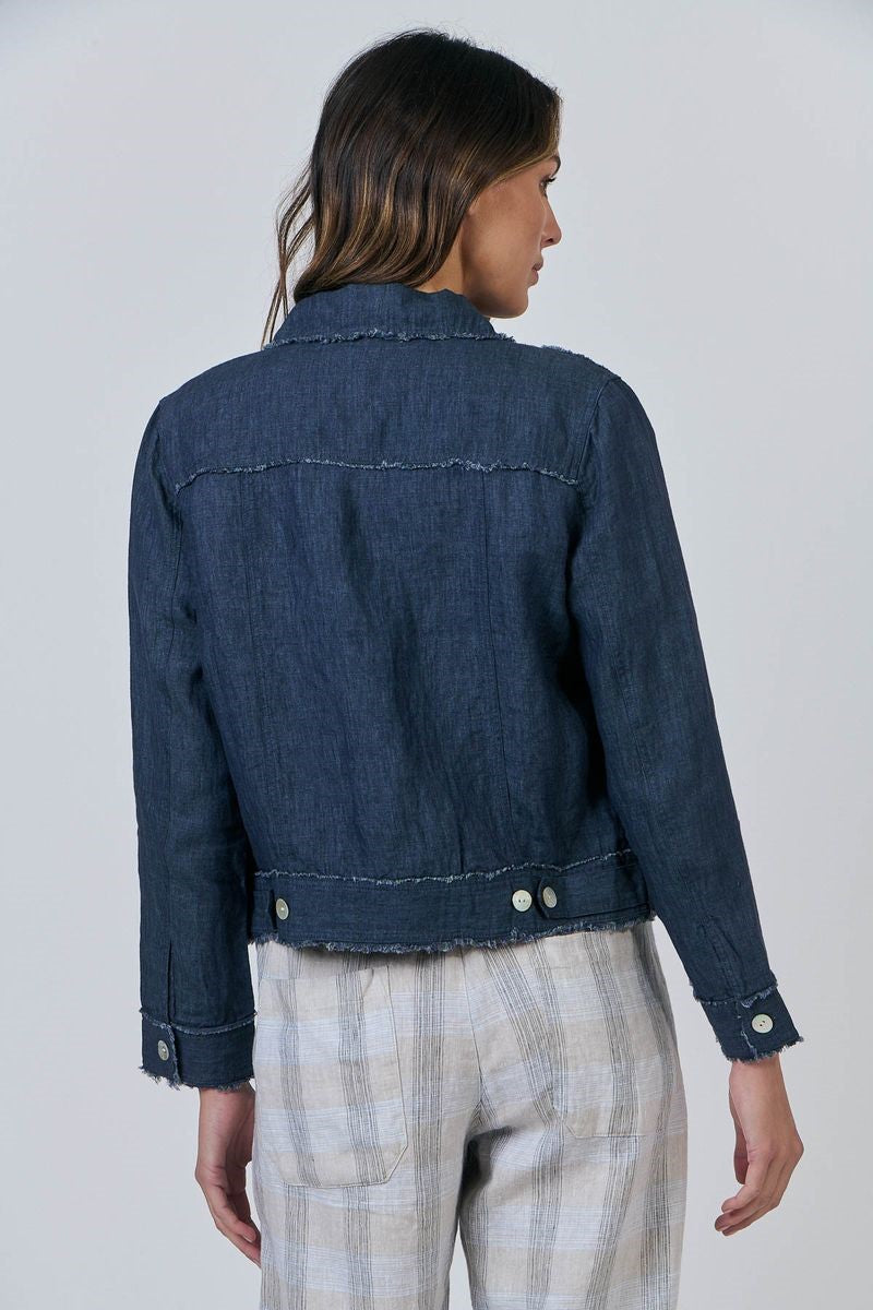 Person wearing a blue denim jacket and plaid pants on a plain background