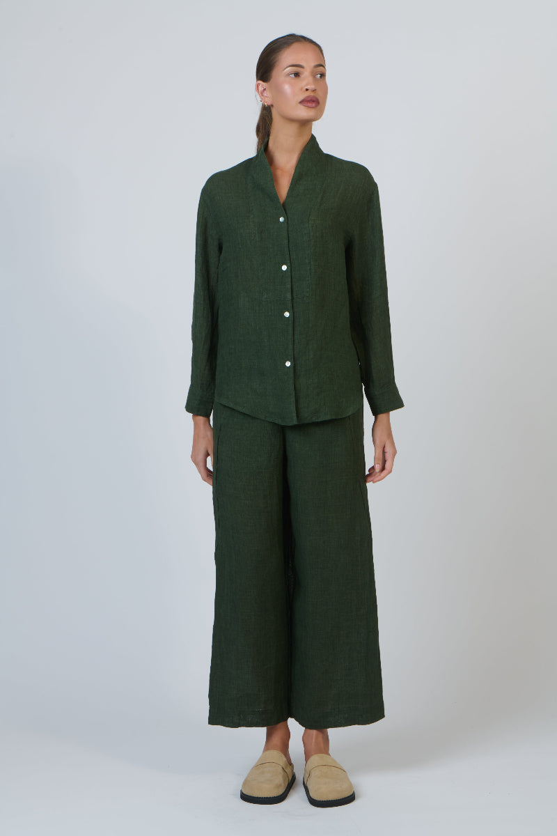 Woman wearing a green outfit with wide-leg pants on a white background