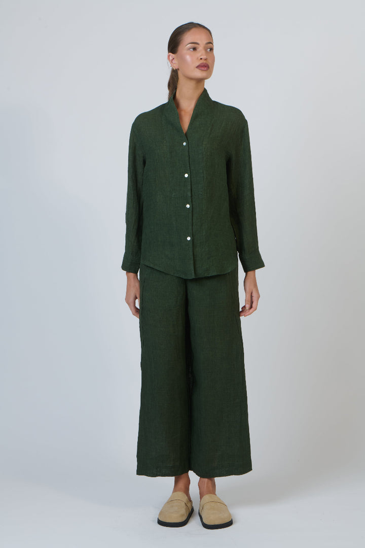 Woman wearing a green outfit with wide-leg pants on a white background