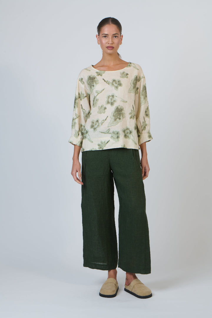 Woman wearing a floral blouse and green pants on a white background