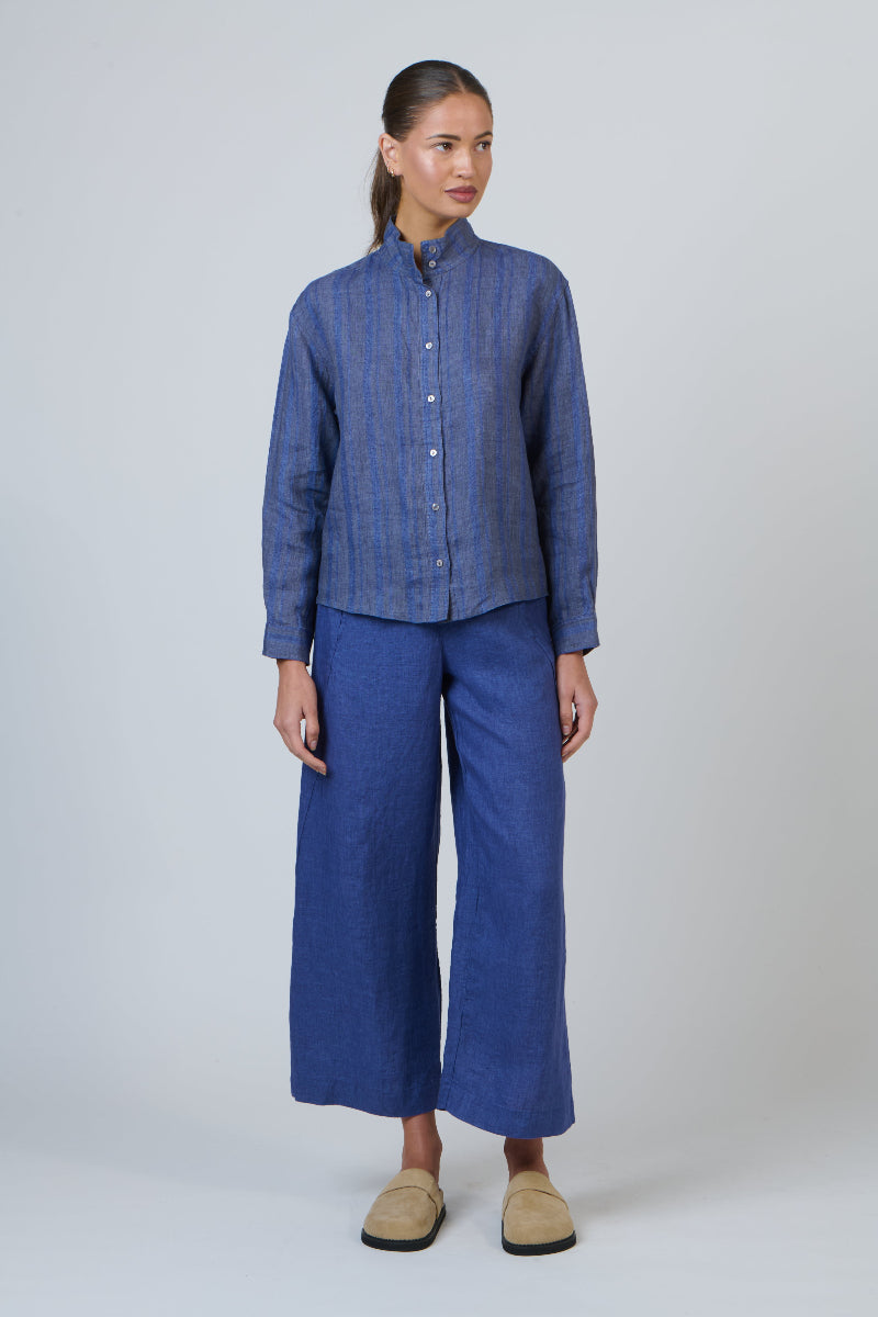 Woman wearing a blue shirt and wide-leg pants on a white background
