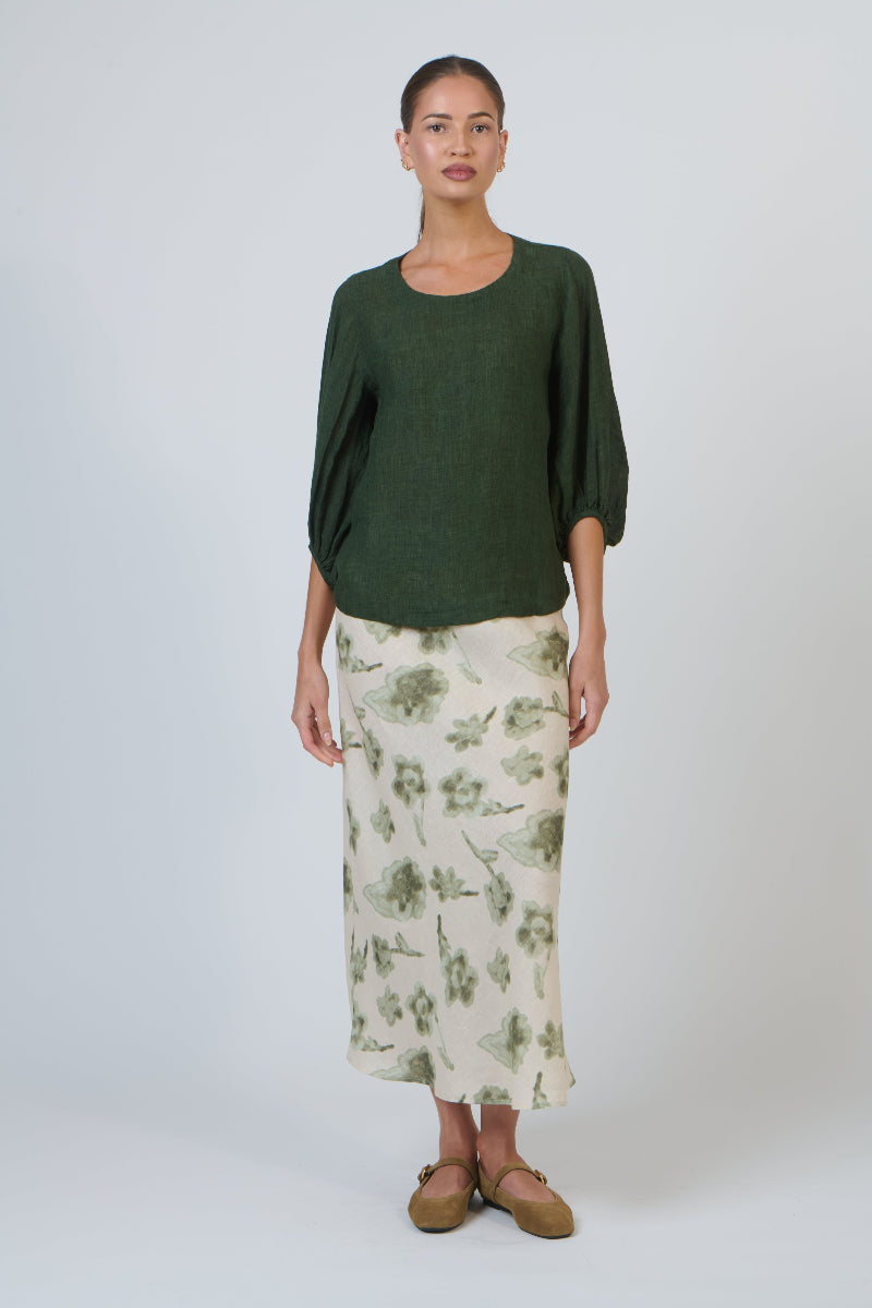 Woman wearing a green top and floral skirt on a white background