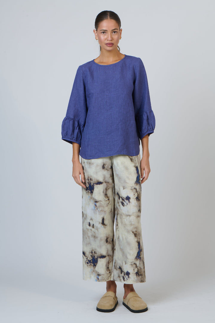 Woman wearing a blue top and patterned pants on a white background