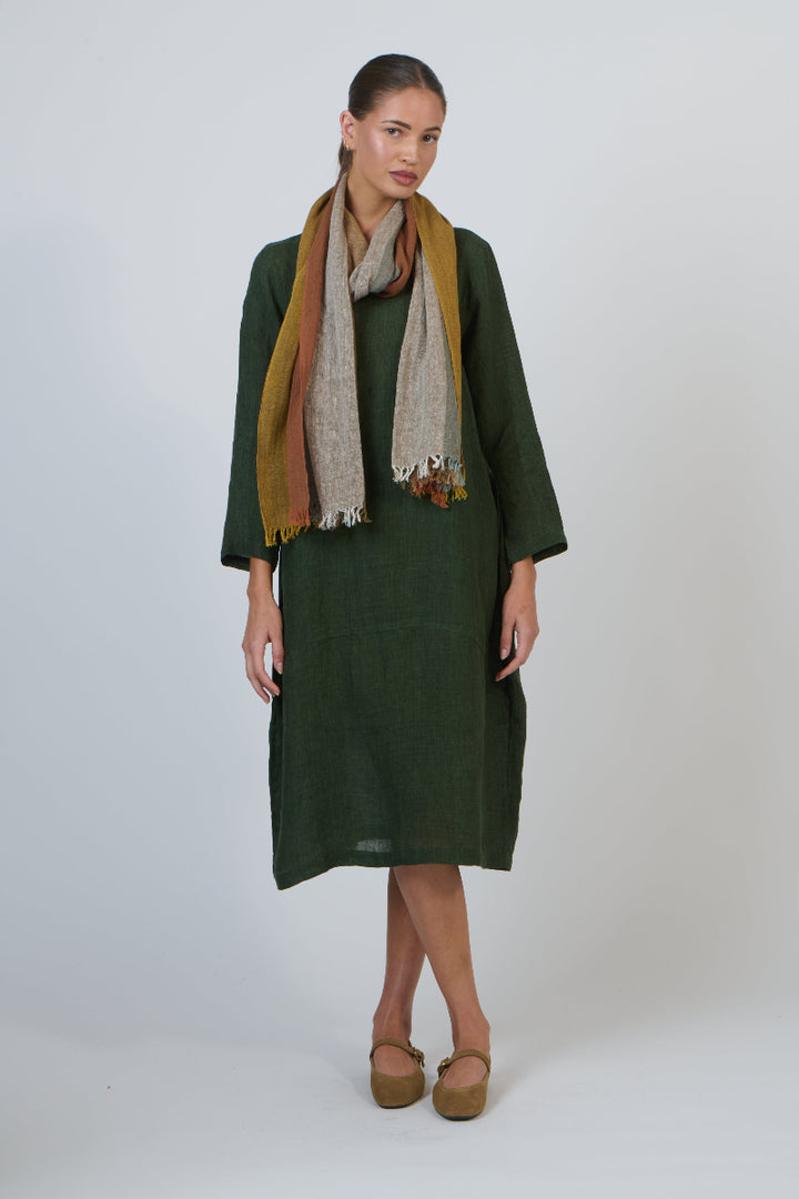 Woman wearing a green dress and patterned scarf on a white background