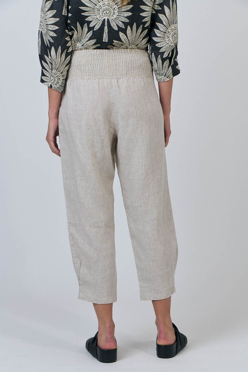 Person wearing beige pants with a black and white patterned top on a white background