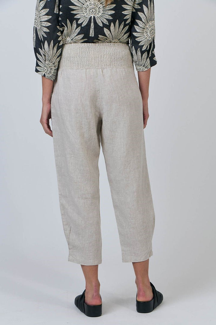 Person wearing beige pants with a black and white patterned top on a white background
