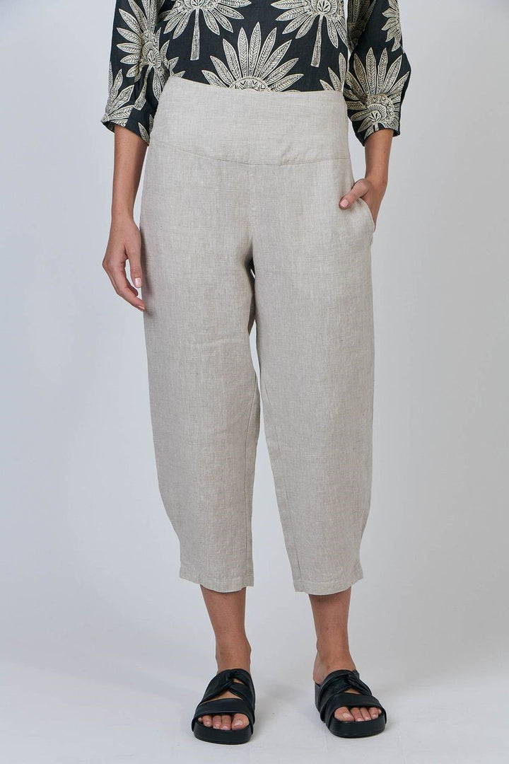 Person wearing beige pants and a black and white patterned top on a white background