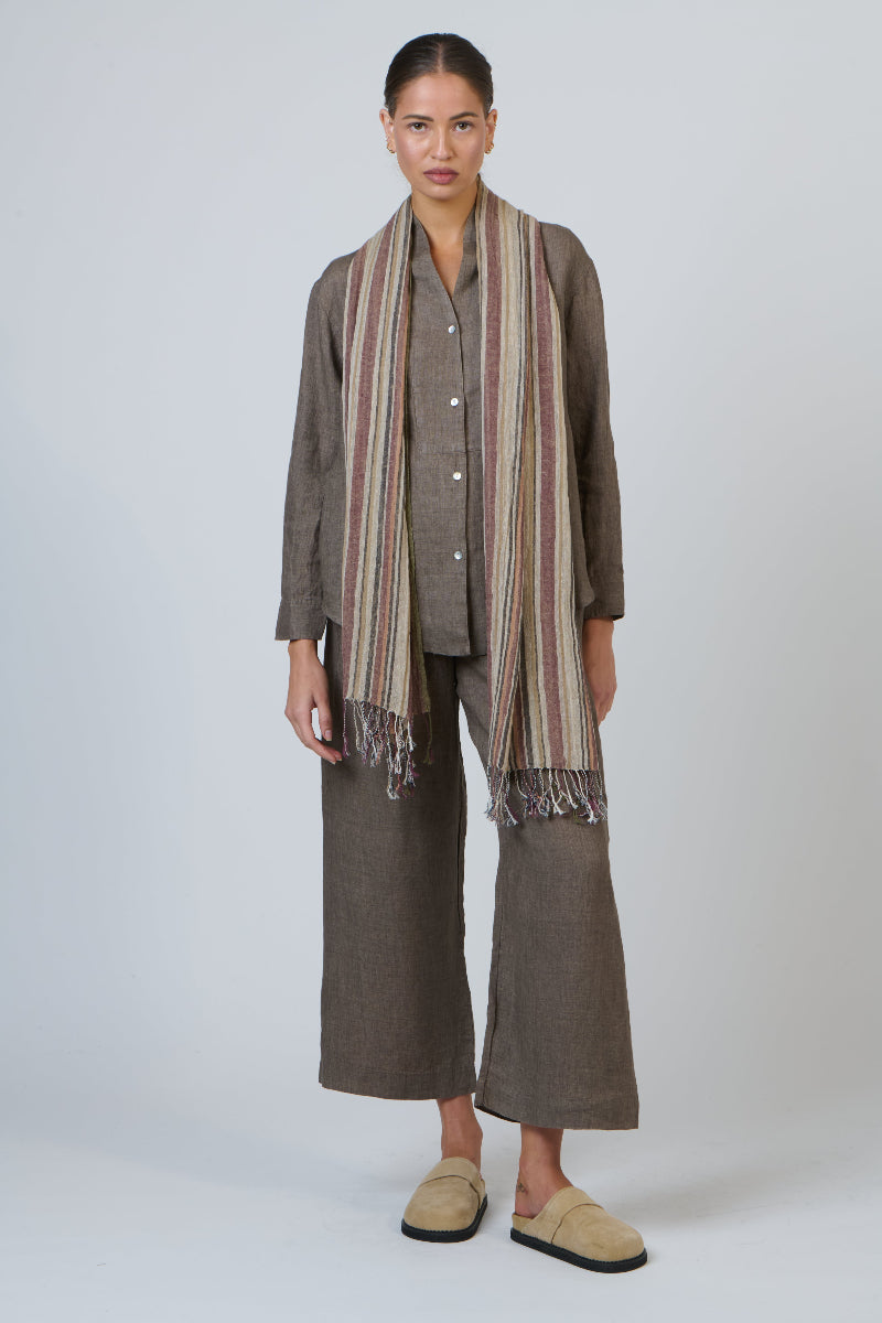 Woman wearing a brown outfit with a striped scarf on a white background