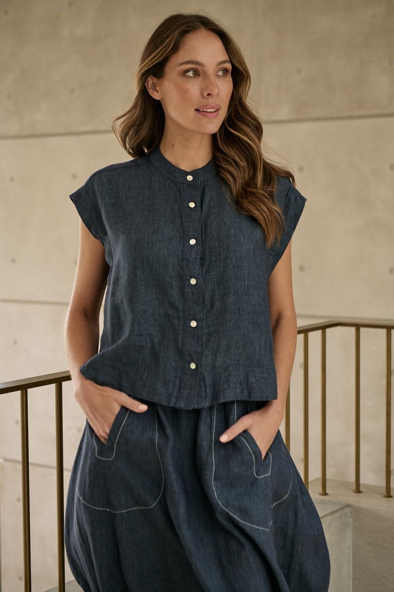 Woman wearing a dark denim outfit with a textured wall background