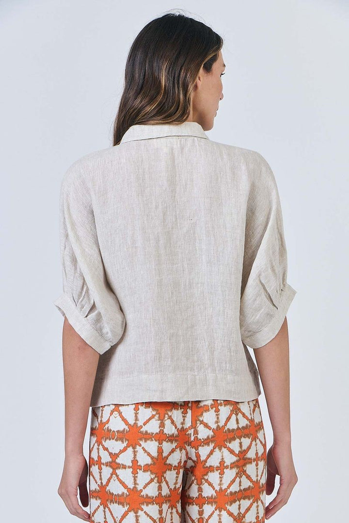 Woman wearing a beige top and patterned pants on a white background