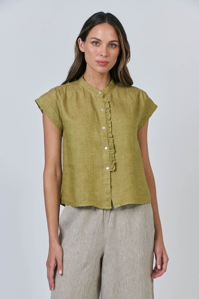 Woman wearing a green blouse with ruffled details on a white background