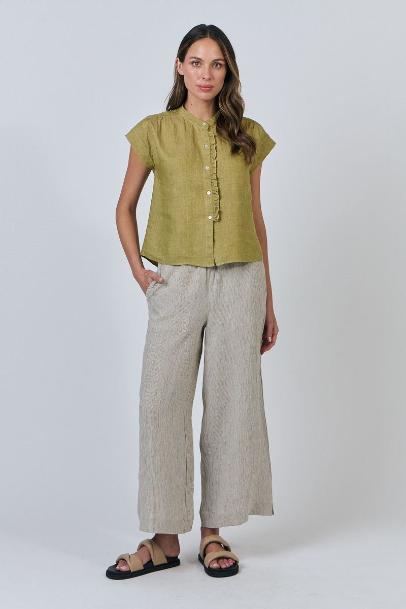 Woman wearing a green top and beige pants on a white background