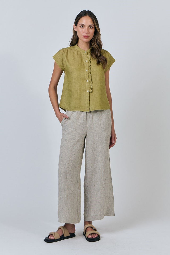 Woman wearing a green top and beige pants on a white background