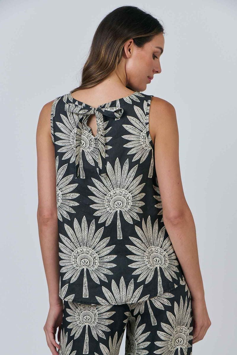 Woman wearing a sleeveless top with floral pattern on a plain background