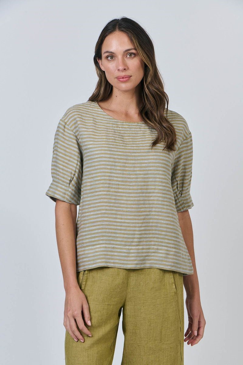 Woman wearing a striped shirt and green pants against a white background
