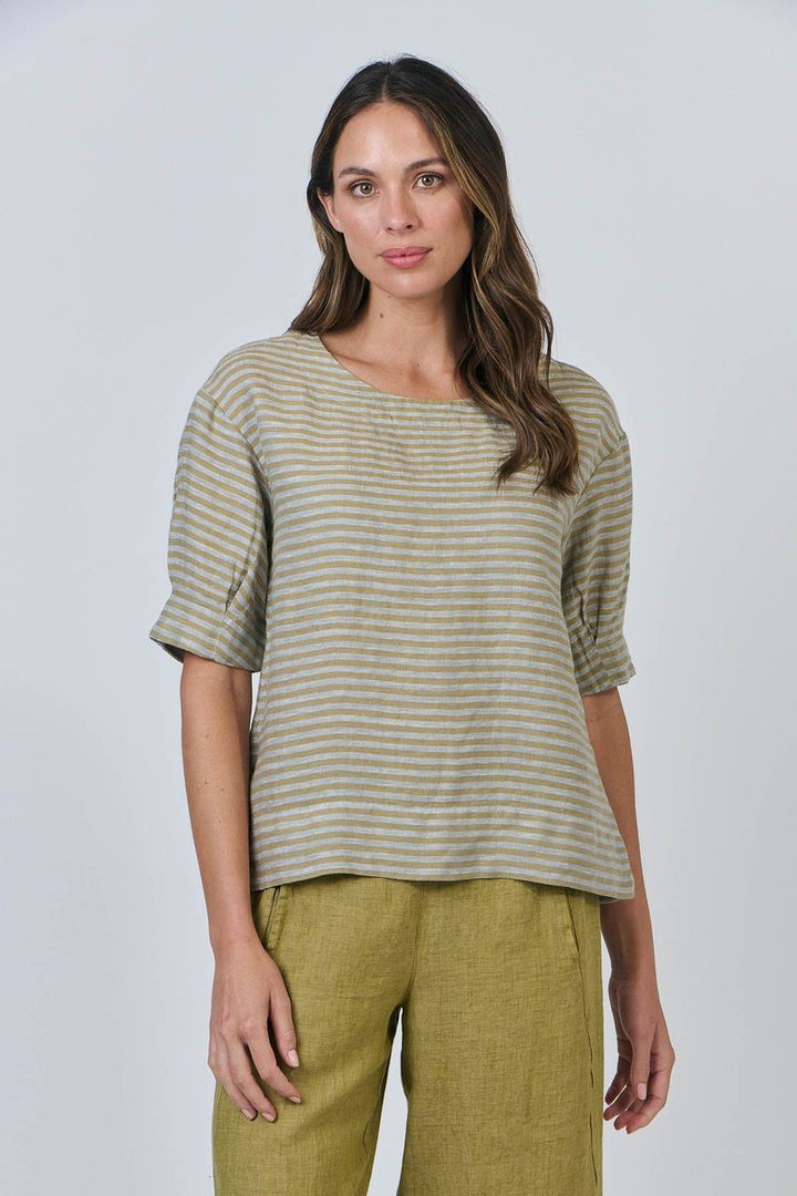 Woman wearing a striped shirt and green pants against a white background