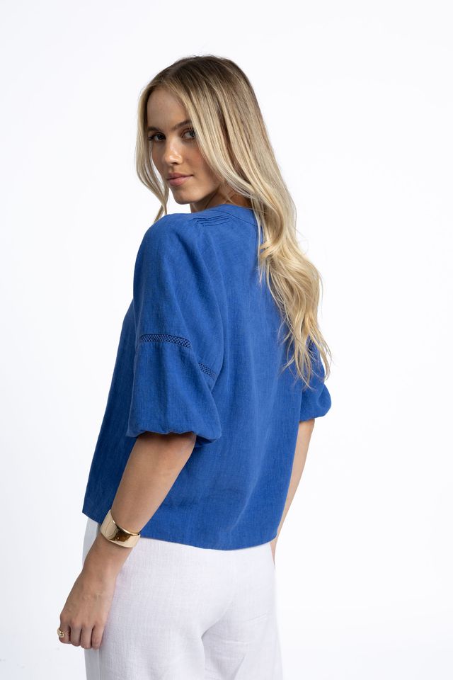 Woman wearing a blue top and white pants on a white background