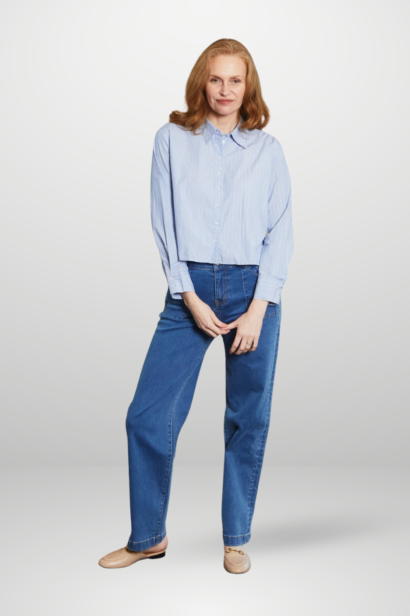 Woman wearing a light blue shirt and dark blue jeans on a white background