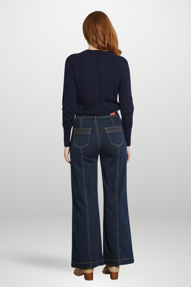 Person wearing a navy sweater and dark blue jeans on a white background