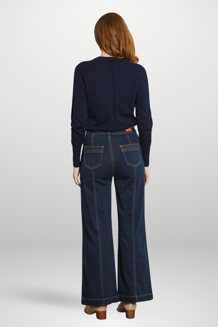 Person wearing a navy sweater and dark blue jeans on a white background