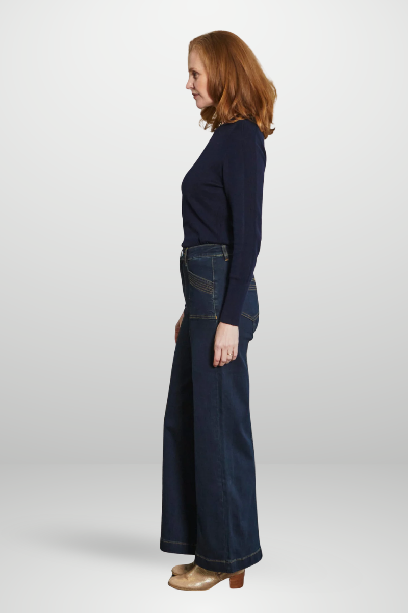 Woman wearing a navy sweater and long navy denim skirt on a white background