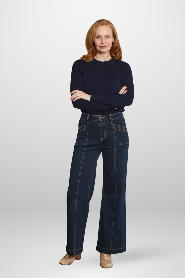 Woman wearing a navy sweater and dark blue jeans on a white background