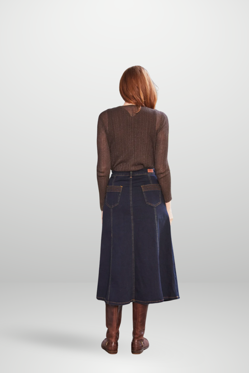 Person wearing a brown sweater and dark denim skirt on a white background
