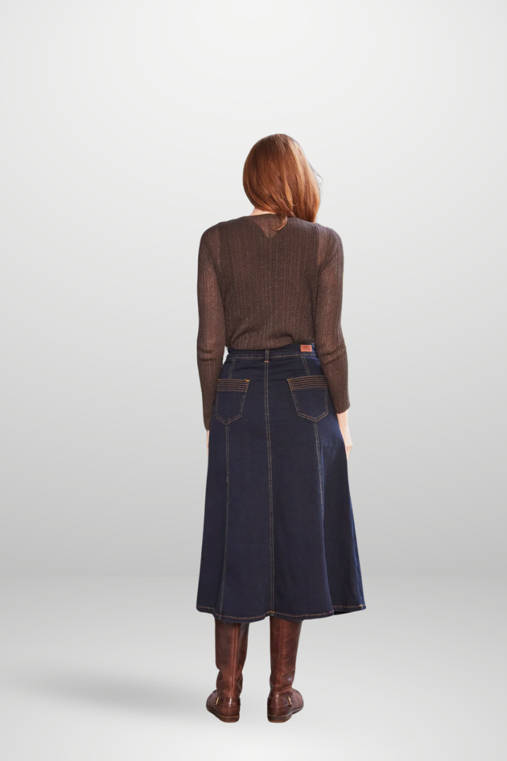 Person wearing a brown sweater and dark denim skirt on a white background