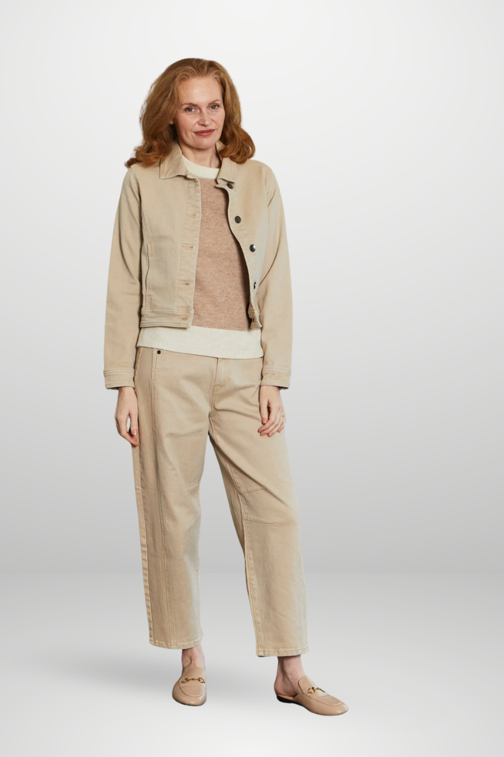 Woman wearing a beige jacket, sweater, and pants on a white background