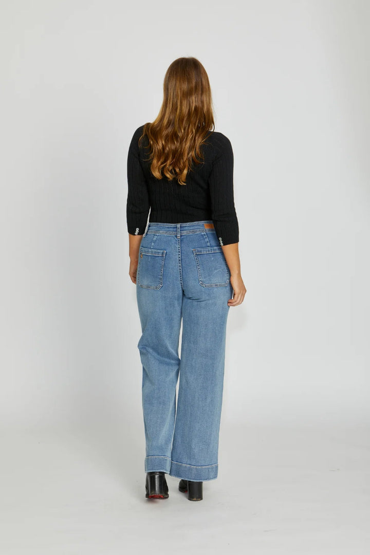 Person wearing blue jeans and a black top on a white background