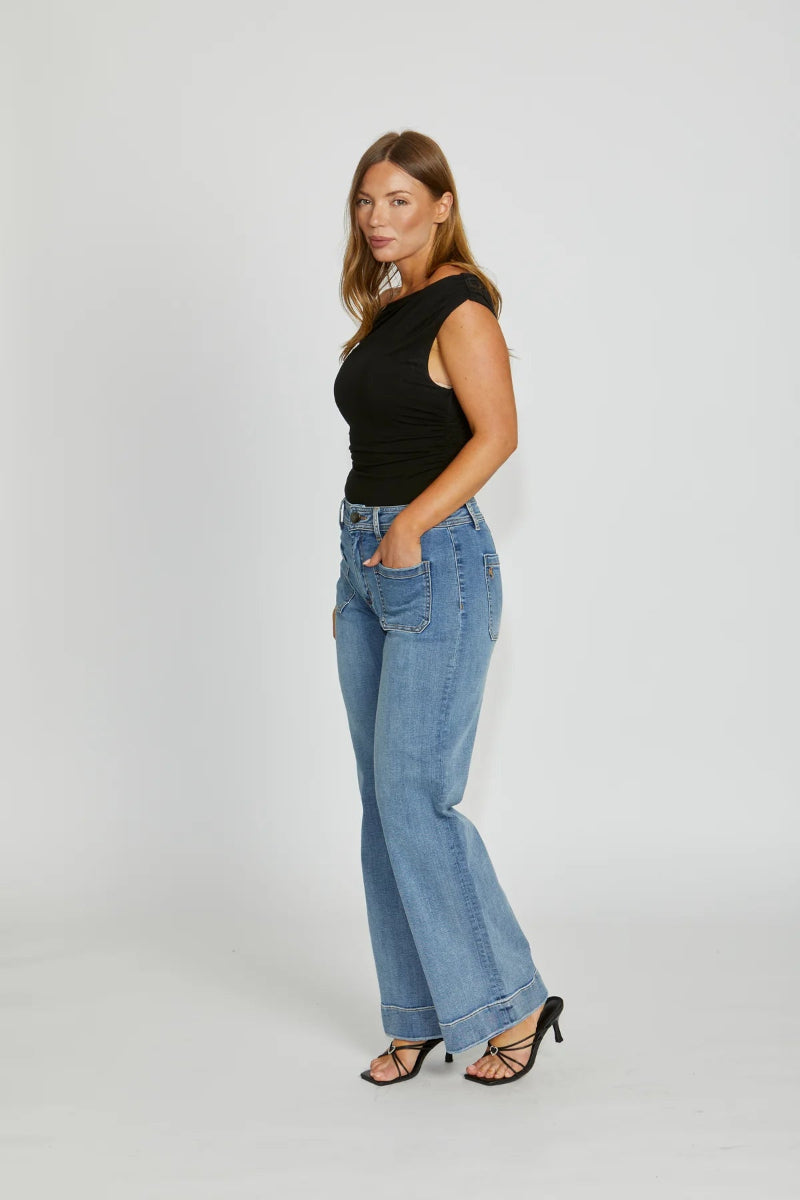 Woman wearing a black top and blue jeans on a white background