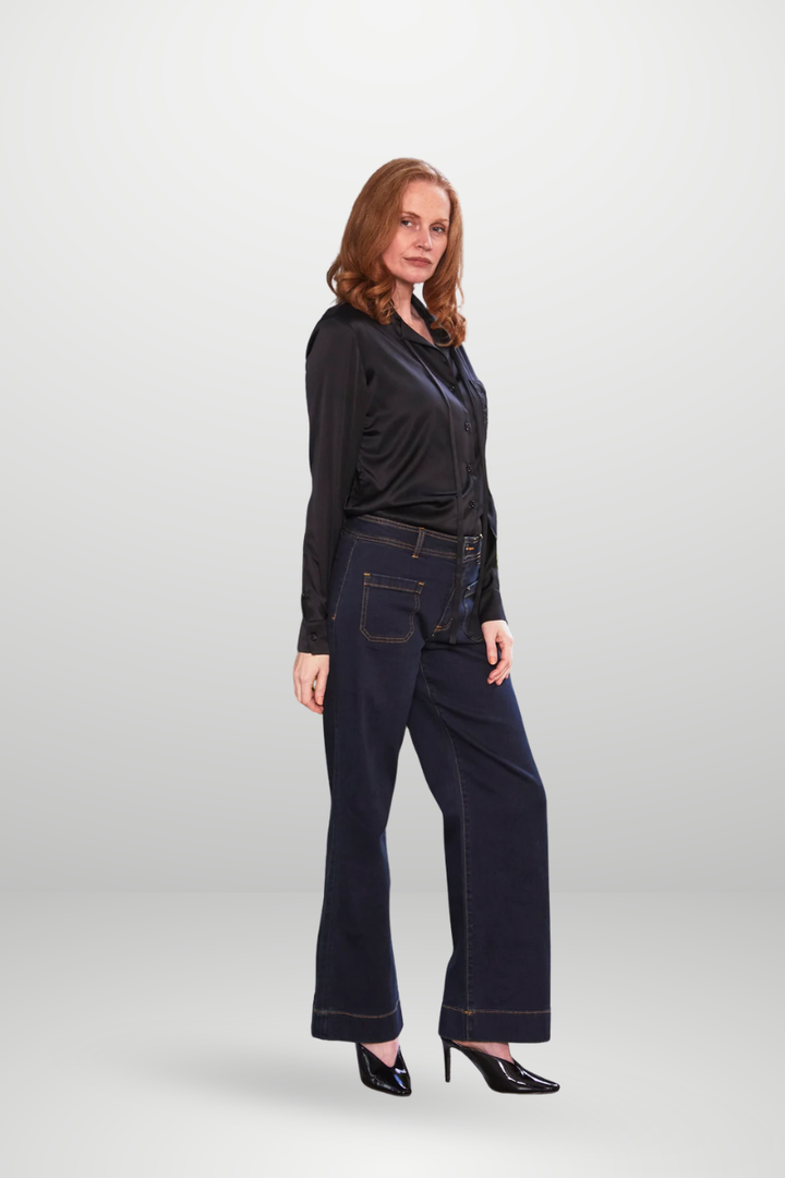 Woman wearing a black top and dark blue jeans on a white background