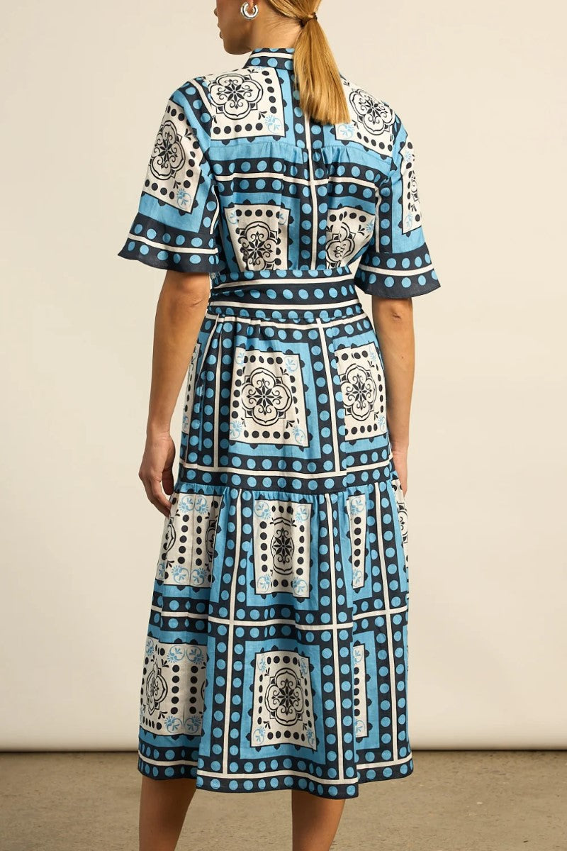 Woman wearing a blue patterned dress against a beige background