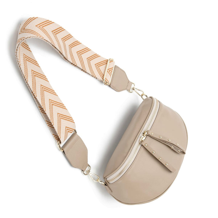 The Obsessed Bag is crafted in soft taupe leather with gold hardware, featuring a wide detachable strap and secure zip details, available at Ivy Vibe.
