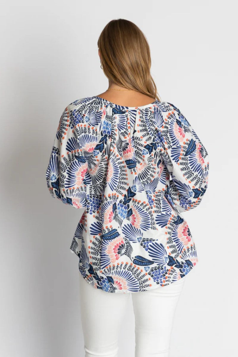 Woman wearing a patterned blouse with a plain background