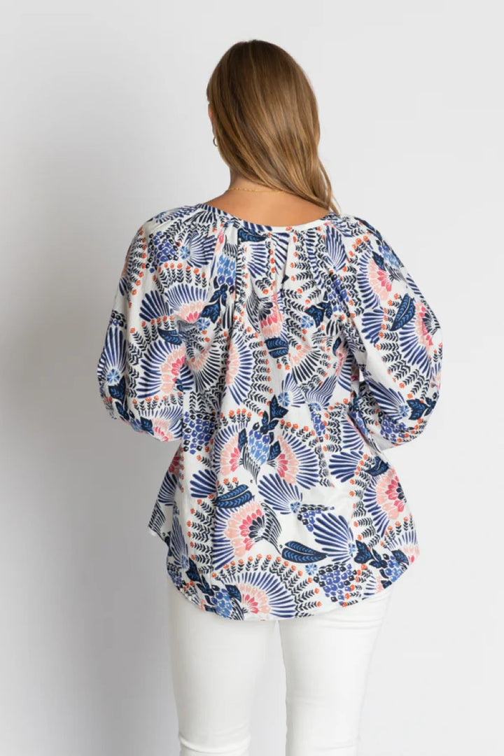 Woman wearing a patterned blouse with a plain background
