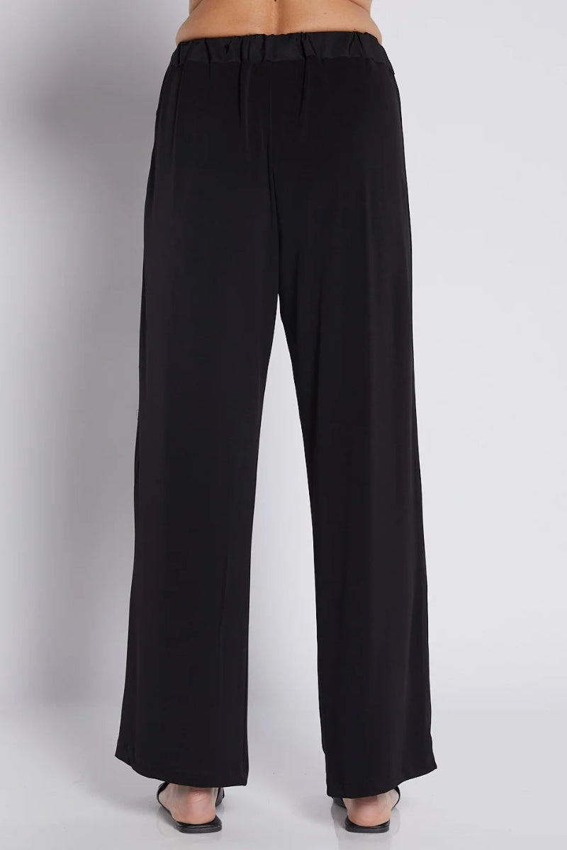 Black wide-leg trousers with an elastic waistband, shown on a model from the back against a light gray studio background.