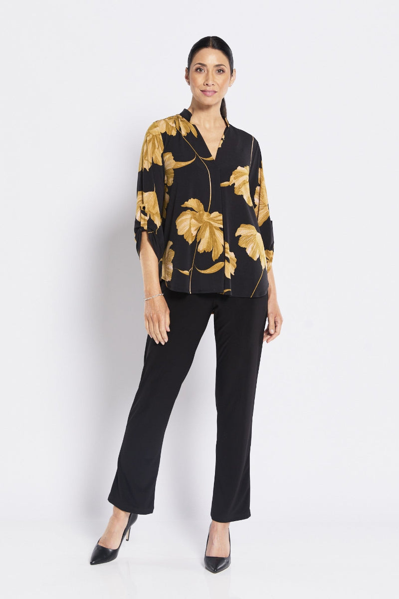 Woman wearing a black floral blouse and black pants on a white background