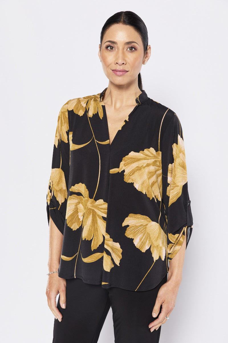 Woman wearing a black blouse with gold floral patterns on a white background