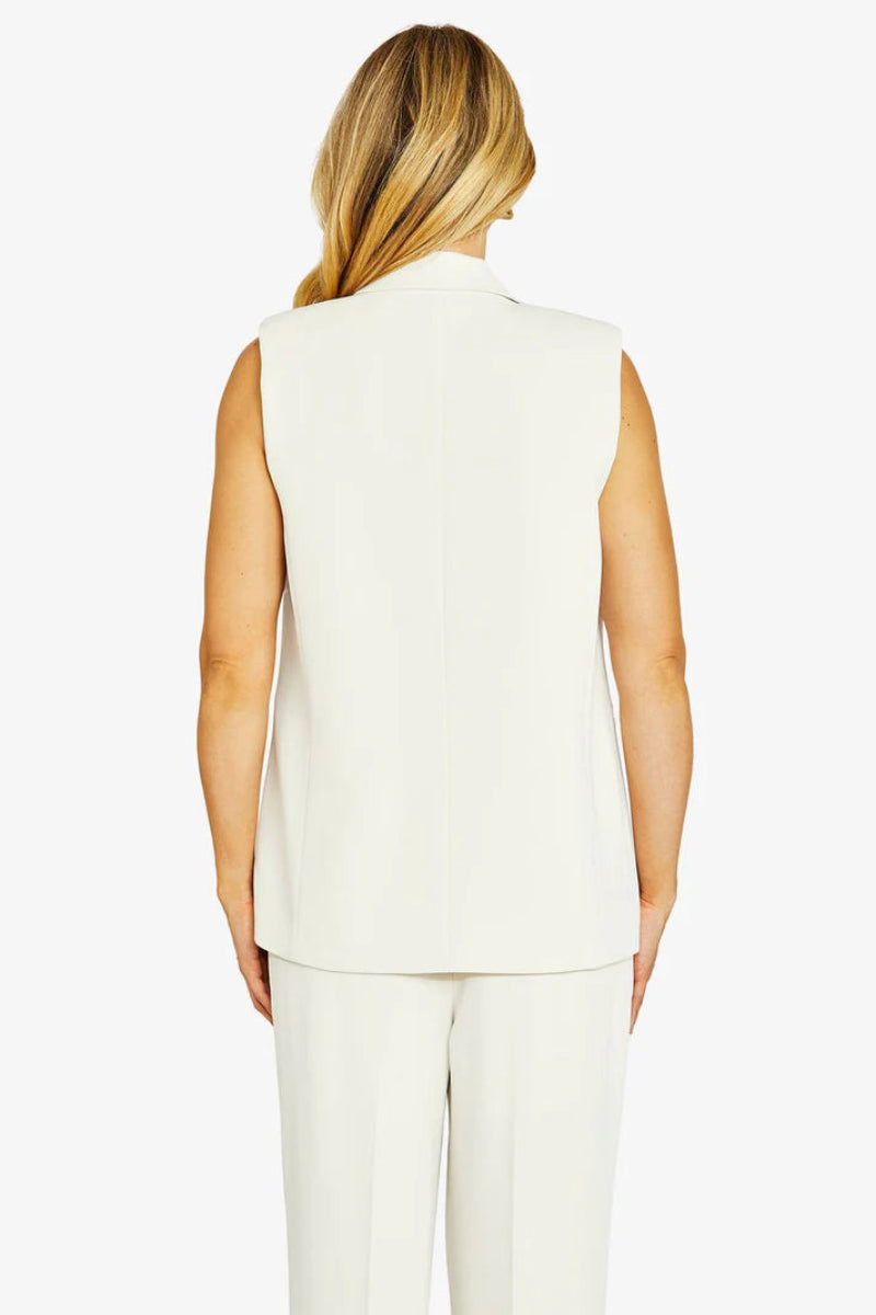 Woman wearing a white sleeveless blazer and pants on a white background